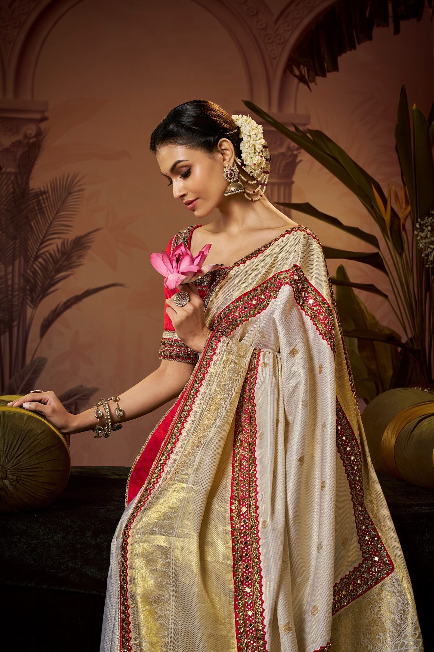 Ivory and gold tissue saree with a red pallu edge, worn with a red blouse and jasmine in the hair