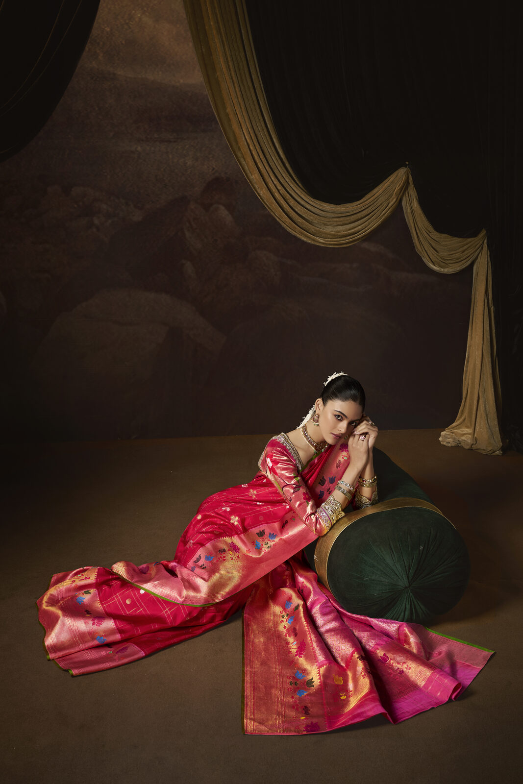 Model in a pink kundan and stone-work saree reclining in the atelier salon