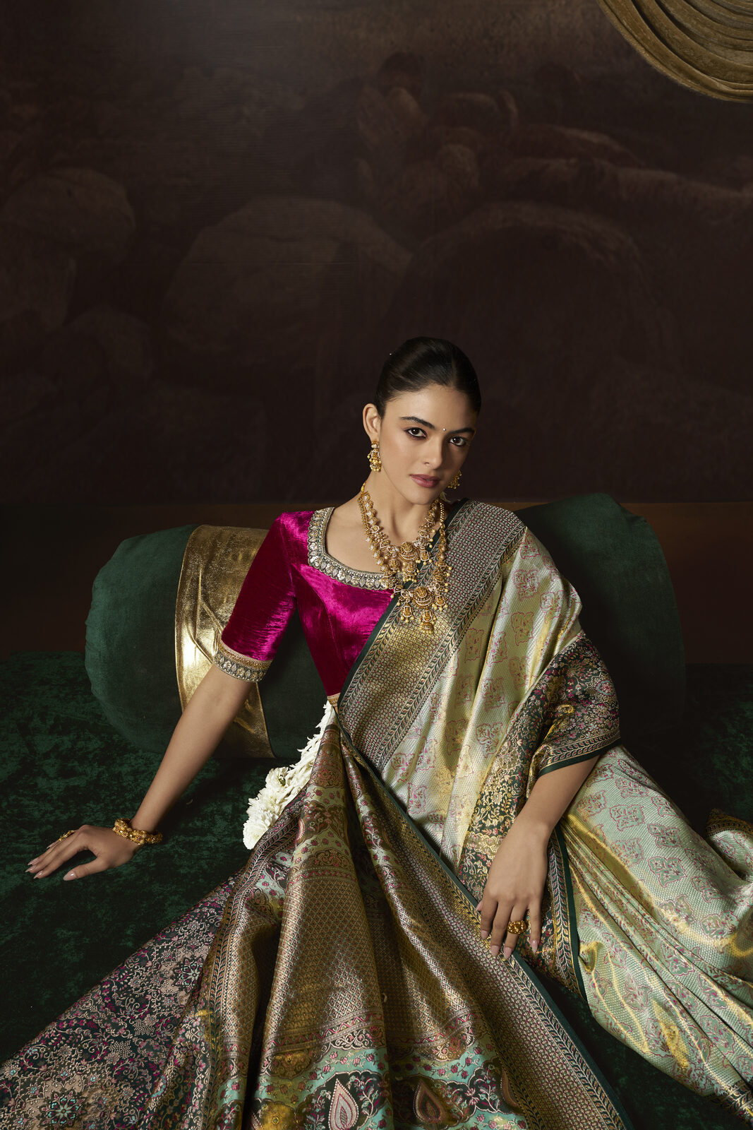 Bride in an emerald and gold kimkhwab reception saree reclining in a heritage salon