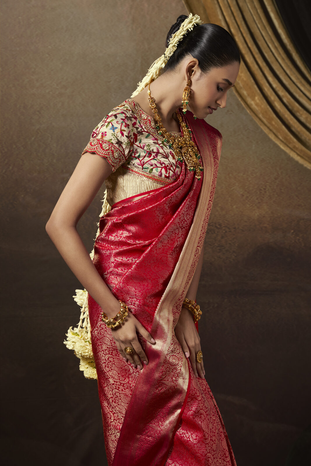 Bride in a deep red handloom bridal saree with gold zari and temple jewellery